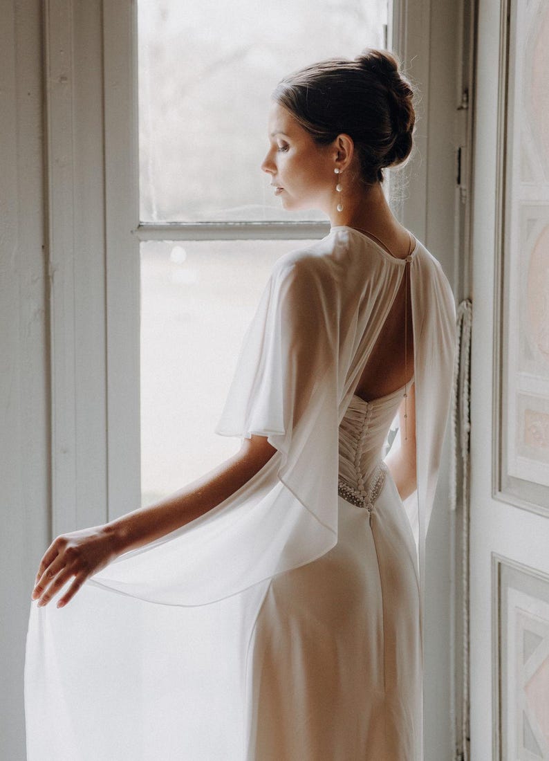 a modern bride wears sheer bridal cape made of light sheer chiffon