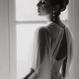 a modern bride wears sheer bridal cape made of light sheer chiffon