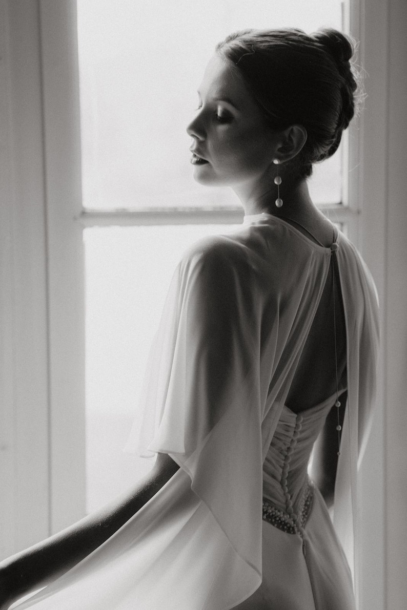 a modern bride wears sheer bridal cape made of light sheer chiffon