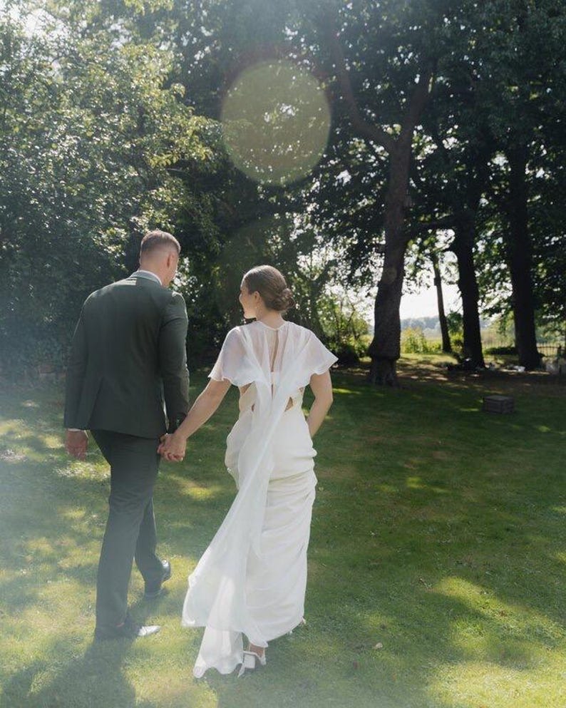 a modern bride wears sheer bridal cape made of light sheer chiffon