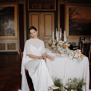 a modern bride wears sheer bridal cape made of light sheer chiffon