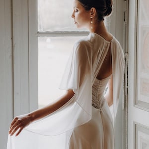 a modern bride wears sheer bridal cape made of light sheer chiffon