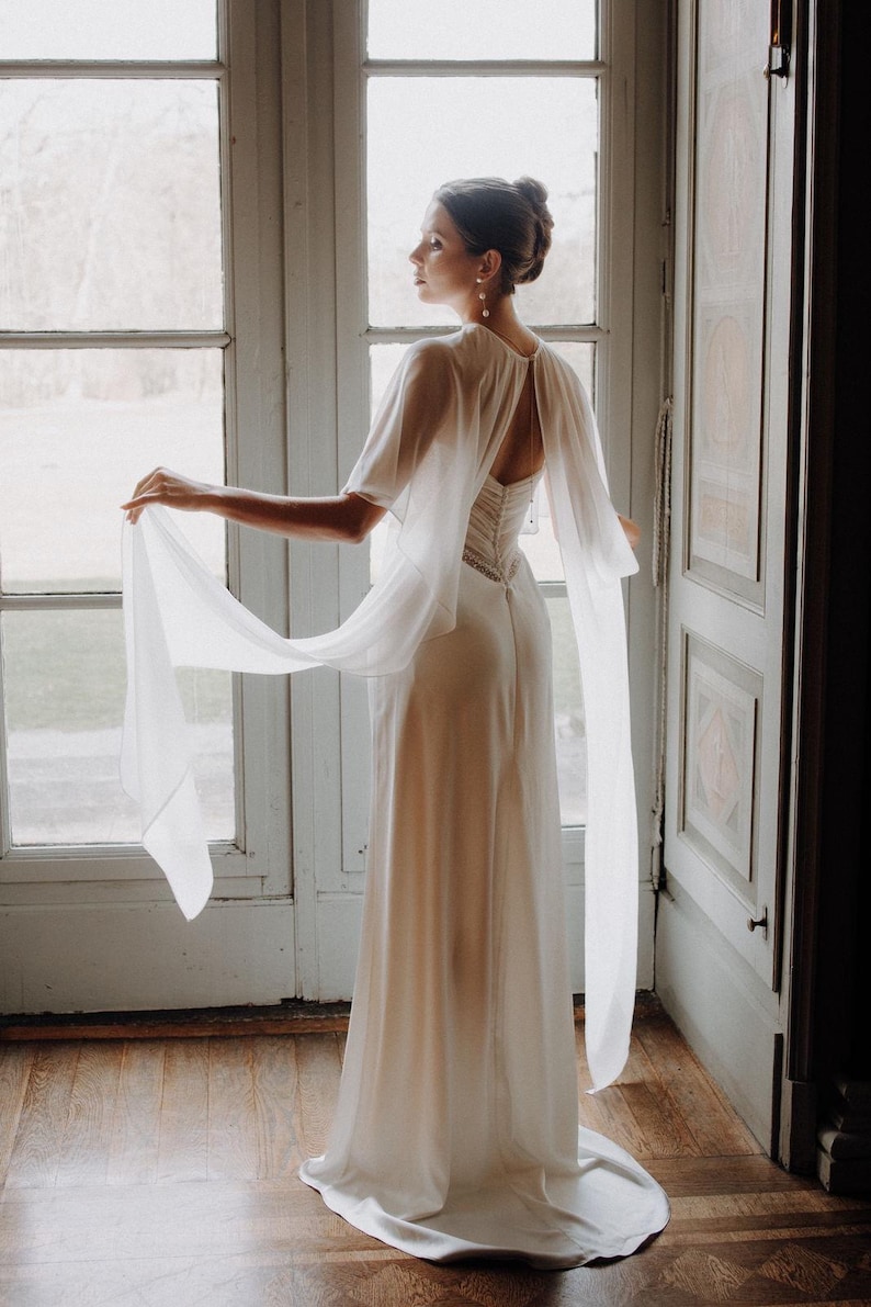 a modern bride wears sheer bridal cape made of light sheer chiffon