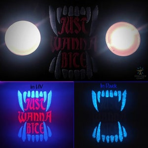 Może przedstawiać: Czarna łatka z białymi szwami, na której widnieje napis "Just Wanna Bite" w kolorze czerwonym. Łatka świeci na niebiesko pod czarnym światłem i na czerwono pod światłem UV.