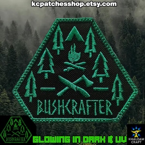Może przedstawiać: Sześciokątna czarna naszywka z neonowo-zielonym haftowanym wzorem przedstawiającym drzewa, ognisko, siekierę i nóż. Słowo "BUSHCRAFTER" jest wyhaftowane poniżej. Widoczny jest również tekst "GLOWING IN DARK & UV", wskazujący na funkcję świecenia w ciemności.