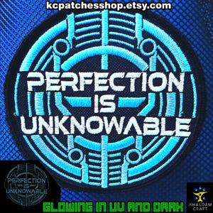 Op de afbeelding: Geborduurde ronde patch met de tekst "PERFECTION IS UNKNOWABLE" in wit en lichtblauw. Het ontwerp bevat geometrische vormen en een zwarte rand. De tekst "GLOWING IN UV AND DARK" staat onderaan.