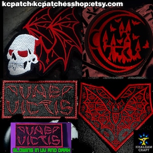 Może przedstawiać: Kolekcja haftowanych naszywek o tematyce gotyckiej i Halloween. Wzory obejmują czaszkę, zamek z nietoperzami, nietoperza oraz napis "QUAER VICTIS". Naszywki są czarne z czerwonymi detalami i świecą w UV i ciemności.