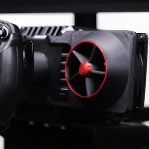 May include: A black racing wheel with a red and black fan attached to it. The fan has a red rim and black blades.
