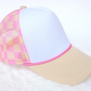 Könnte beinhalten: Basecap mit weißem Frontpanel, beigem Schirm und pinkfarbenem Seildetail. Die Mesh-Rückseite hat ein rosa-beiges Karomuster. Die Kappe hat einen gebogenen Schirm und einen Knopf oben.