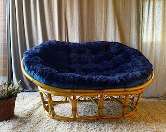 May include: A blue and brown round chair with a woven bamboo frame. The chair is made of a soft, plush fabric and has a comfortable, rounded shape.