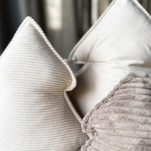 May include: Three decorative tree-shaped pillows in varying shades of white and beige. The front pillow has a ribbed texture, while the others have a smooth, soft appearance. These pillows are designed for home decor.