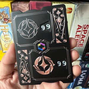 Contador de tradiciones de torneos profesionales con números negros y retención magnética para juegos de mesa de rol Lorcana TCG. Cuenta del 0 al 99. Tamaño de carta estándar