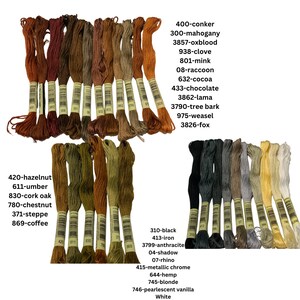 May include: A collection of embroidery floss spools in various shades of brown, green, and gray. The spools are labeled with numbers and color names, such as 420-hazelnut, 611-umber, 830-cork oak, 780-chestnut, 371-steppe, 869-coffee, 400-conker, 300-mahogany, 3857-oxblood, 938-clove, 801-mink, 08-raccoon, 632-cocoa, 433-chocolate, 3862-lama, 3790-tree bark, 975-weasel, 3826-fox, 310-black, 413-iron, 3799-anthracite, 04-shadow, 07-rhino, 415-metallic chrome, 644-hemp, 745-blonde, 746-pearlescent vanilla, and White.