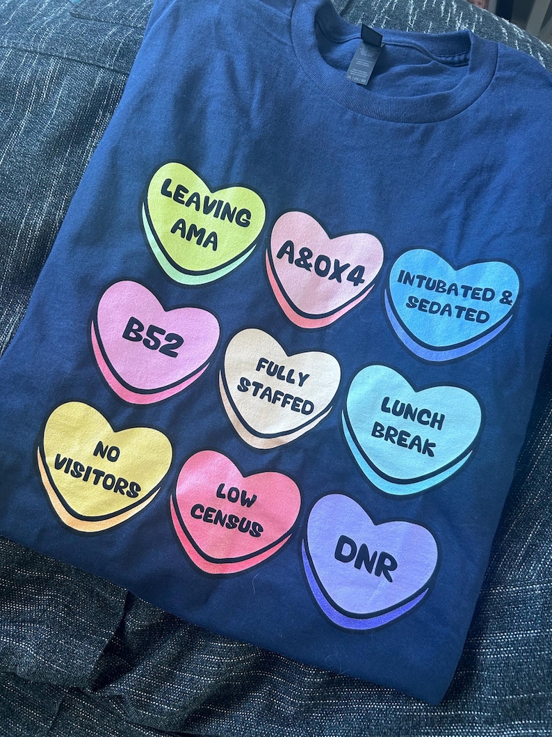 Funny nurse Valentine shirt featuring candy hearts with medical terms like “A&Ox4,” “B52,” and “Fully Staffed.” Perfect nurse humor tee for Valentine’s Day or any shift. Made on comfy Gildan 5000 unisex shirts with high-quality print. Ideal gift for nurses, techs, or healthcare workers who love a laugh. Support a fellow nurse and grab this sweet and sassy hospital-themed shirt today!