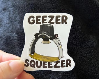 May include: A white sticker with a black and white illustration of a horse riding device. The sticker says "Geezer Squeezer" and "Lucas 3" in black text.