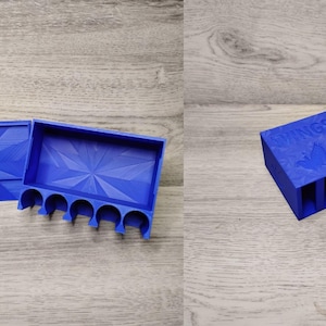 May include: A blue 3D-printed Wingspan game component organizer. The organizer has a lid and a tray with slots for game pieces. The lid and tray have a geometric design. The text "Wingspan" is visible on the top.