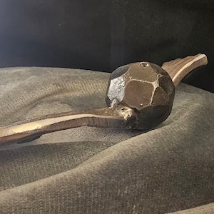 Könnte beinhalten: Eine silberne Vogelskulptur aus Metall mit einem strukturierten, kugelförmigen Körper und einem langen, gebogenen Schnabel.