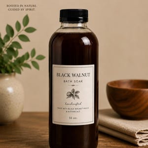 Puede incluir: Una botella de plástico transparente llena de un baño líquido de color marrón oscuro. La etiqueta dice BLACK WALNUT BATH SOAK, handcrafted, made with black walnut hulls & botanicals, 16 oz. La botella tiene una tapa negra y etiqueta blanca.