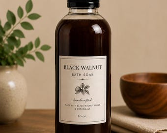 May include: A clear plastic bottle filled with dark brown liquid bath soak. The label reads BLACK WALNUT BATH SOAK, handcrafted, made with black walnut hulls & botanicals, 16 oz. The bottle has a black screw cap and a white rectangular label.