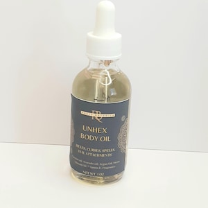 May include: A clear glass bottle with a gold label that reads "UNHEX BODY OIL" and "HEXES, CURSES, SPELLS, EVIL ATTACHMENTS". The bottle has a white dropper top and contains a light yellow liquid. The bottle is 1 ounce.