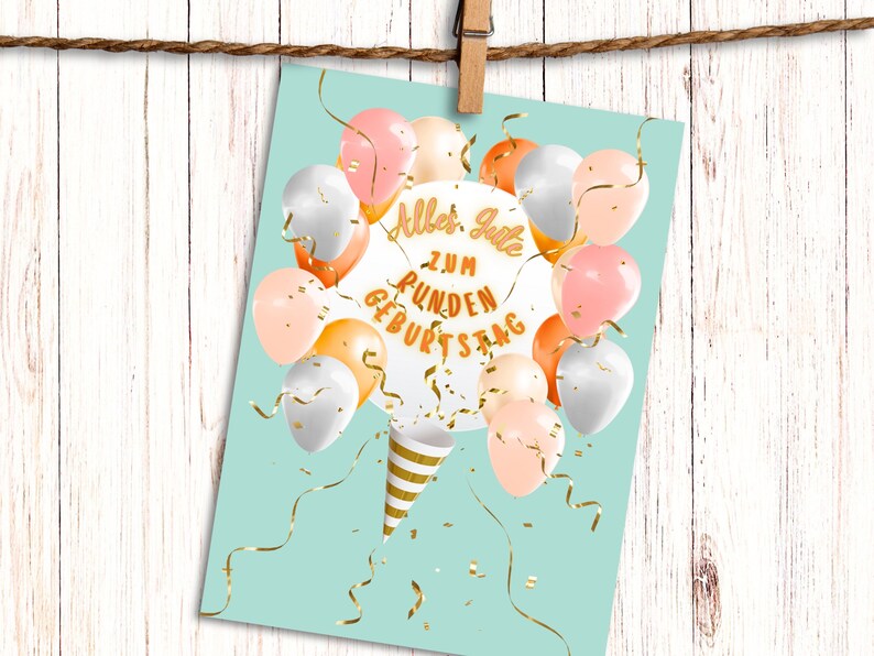 May include: A turquoise blue card with a white circle in the centre that says "Alles Gute zum runden Geburtstag". The circle is surrounded by pastel pink, peach, and silver balloons with gold confetti.