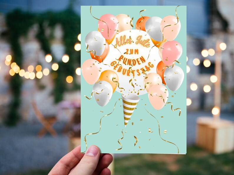 May include: A light blue card with a white circle in the centre that says "Alles Gute zum runden Geburtstag". The circle is surrounded by colourful balloons and gold confetti.