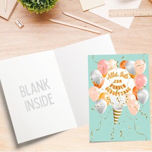 May include: A light blue card with a white inside. The front of the card has a design of balloons in shades of pink, peach, and silver with gold confetti and ribbons. The text on the card reads "Alles Gute zum runden Geburtstag".