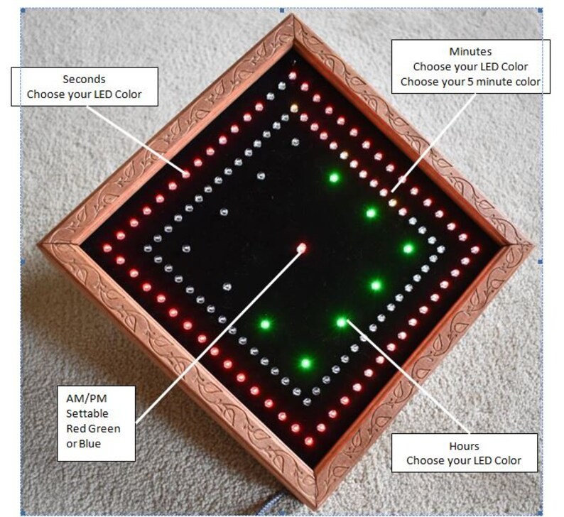 May include: A diamond-shaped LED clock with a brown wooden frame. The clock face is black, with red, green, and white LED lights indicating the time. Text on the image indicates options for LED colour customisation for seconds, minutes, hours, and AM/PM.