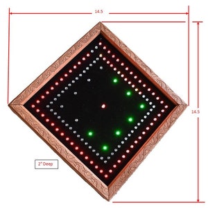 May include: A square LED sign with a dark background and a copper-coloured frame. The sign is 36.8 cm wide and deep, and 5.1 cm deep. It features red, green, and white LED lights arranged in a pattern.