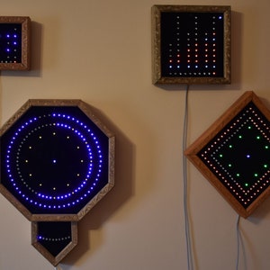 May include: Four framed LED light displays with wooden frames. The displays are various shapes, including a square, rectangle, octagon, and diamond. The lights are blue, green, red, and white, creating patterns. Each display is connected to a power source.
