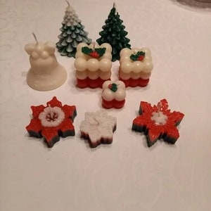 May include: Assortment of Christmas-themed candles, including a bell, two pine trees, two snowflake designs, and two layered cakes with holly accents.