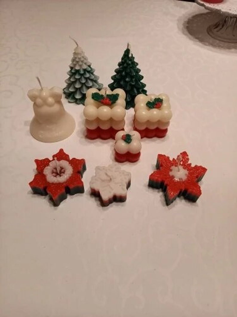 May include: Assortment of Christmas-themed candles, including a bell, two pine trees, two snowflake designs, and two layered cakes with holly accents.