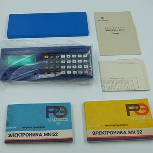Könnte beinhalten: Ein blauer und schwarzer Taschenrechner mit grünem Display, beschriftet mit "Электроника МК-52" und verpackt mit Bedienungsanleitungen.