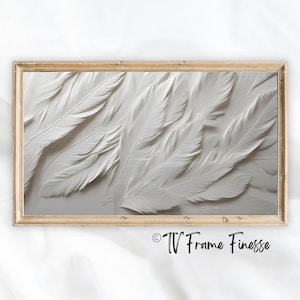 May include: A framed print of a white feather design. The feathers are arranged in a layered pattern, creating a textured and abstract look. The frame is a simple, light wood.