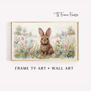 Op de afbeelding: Een ingelijst kunstwerk met een bruin konijn te midden van kleurrijke wilde bloemen. Het kunstwerk heeft een textuur en staat tegen een zachte, lichte achtergrond. De lijst is goudkleurig en de tekst "FRAME TV ART • WALL ART" staat eronder.