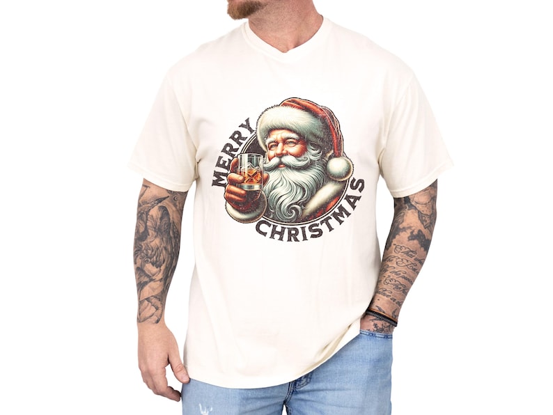 Christmas drinking shirt graphic tee. The t shirt has a distressed, vintage Santa that is holding a glass of whiskey or bourbon on the rocks. The tshirt says Merry Christmas. Comfort Colors tee, short sleeves, crewneck
