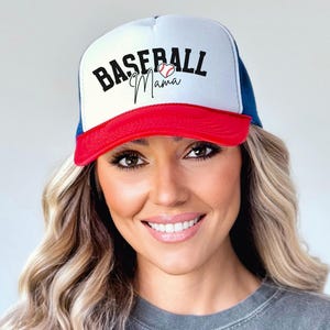 May include: A white, red, and blue baseball cap with a mesh back. The front of the cap has the text "Baseball Mama" in black with a red heart and a baseball graphic.