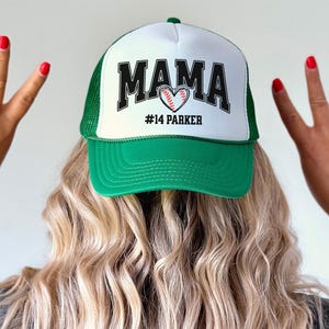 Custom baseball mom hat. the baseball hat says mama and has a baseball shaped heart in the center. the baseball mom trucker hat is personalized with the player name and number. adjustable, mesh back, baseball trucker hat