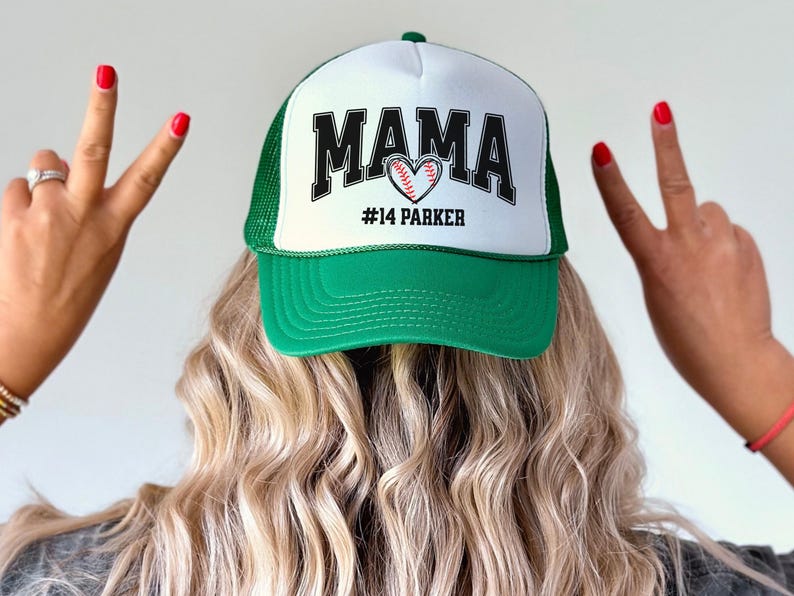 Custom baseball mom hat. the baseball hat says mama and has a baseball shaped heart in the center. the baseball mom trucker hat is personalized with the player name and number. adjustable, mesh back, baseball trucker hat