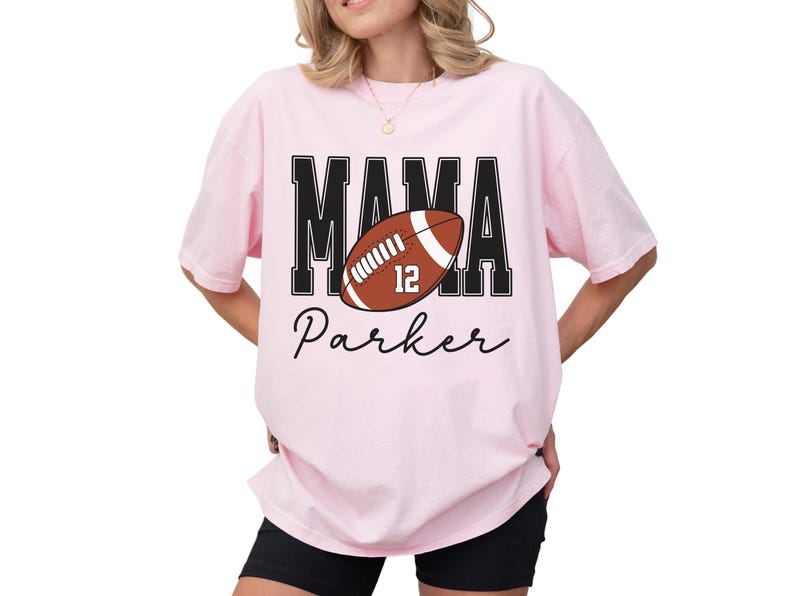 Custom Football Mama Shirt. The tshirt says football mama in varsity font and is personalized with the players number on a large football and name below it. Comfort Colors tee, crewneck, short sleeves football mom t shirt