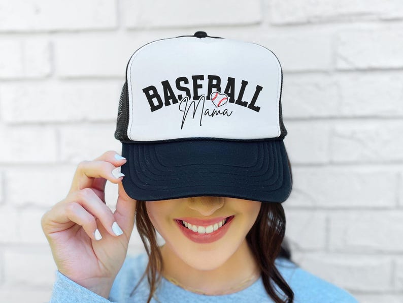 May include: A black and white trucker hat with a white mesh back. The front of the hat has the text "Baseball Mama" in black with a red and white baseball graphic.