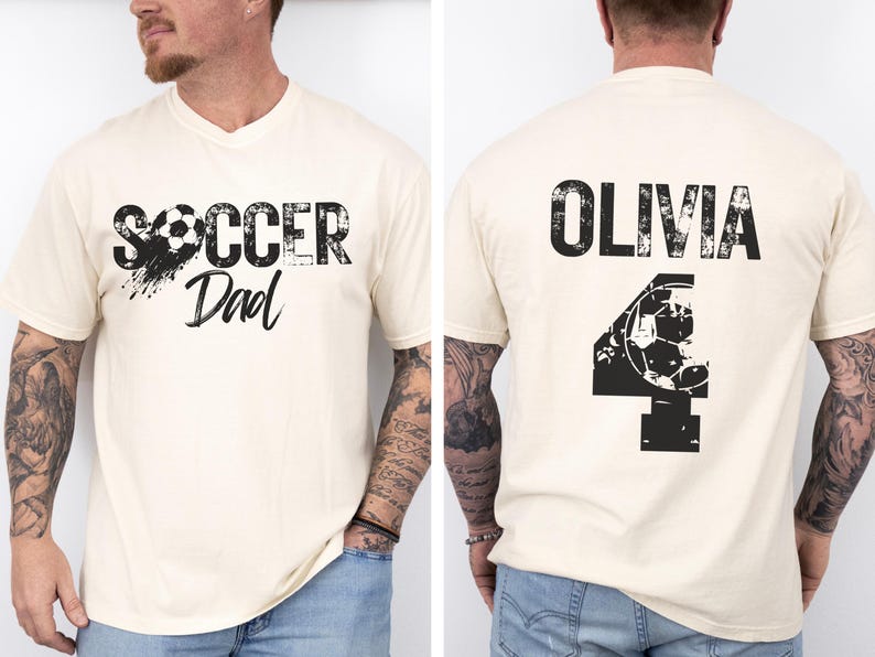 May include: A white t-shirt with a black graphic that says "Soccer Dad" with a soccer ball. The back of the shirt has a black graphic with the name "Olivia" and the number "4" with a soccer ball.