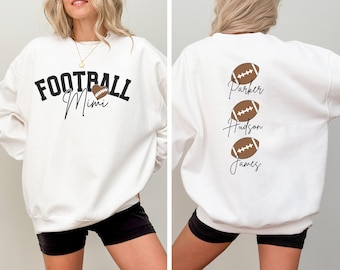 Könnte beinhalten: Weißer Pullover mit dem Text "FOOTBALL Mimi" und einer Fußballabbildung auf der Vorderseite. Die Rückseite des Pullovers hat drei Fußballabbildungen mit den Namen "Parker", "Hudson" und "James" unter jeder.