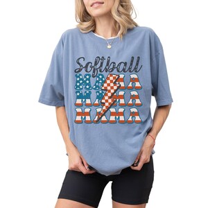 Retro patriotic softball mama shirt for 4th of July and Memorial day. The t shirt says, softball in black distressed script and the word mama repeated 3 times in a red white and blue USA flag font. A checkered lightning bolt down the middle