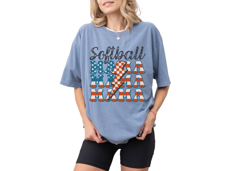 Retro patriotic softball mama shirt for 4th of July and Memorial day. The t shirt says, softball in black distressed script and the word mama repeated 3 times in a red white and blue USA flag font. A checkered lightning bolt down the middle