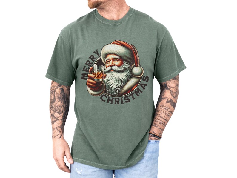 Christmas drinking shirt graphic tee. The t shirt has a distressed, vintage Santa that is holding a glass of whiskey or bourbon on the rocks. The tshirt says Merry Christmas. Comfort Colors tee, short sleeves, crewneck
