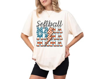 May include: A white t-shirt with the text "Softball Mama" in black lettering. The text is layered with an American flag design and a lightning bolt graphic.