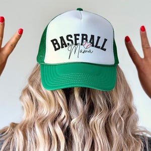 May include: A green and white baseball cap with a mesh back. The front of the cap has the text "Baseball Mama" with a baseball and heart graphic.