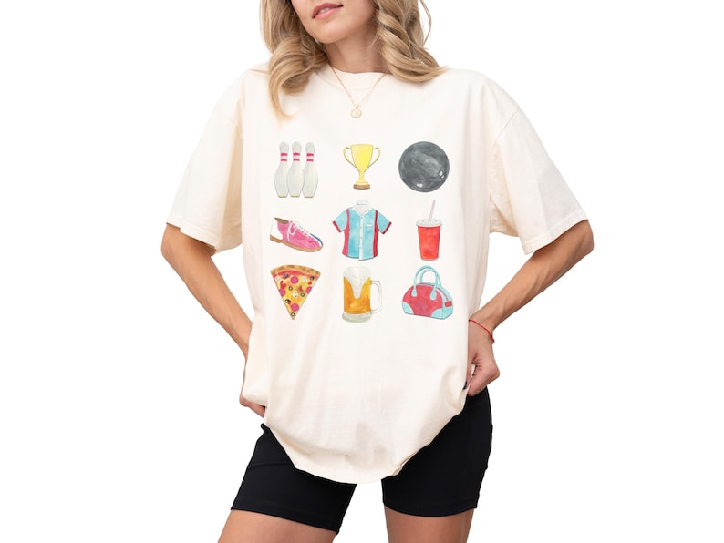 Retro bowling shirt for women. The tshirt has watercolor graphics and features bowling pins, trophy, bowling ball, shoes, shirt, soda, pizza, beer and a bowling bag. Short sleeves, crewneck, comfort colors, ivory