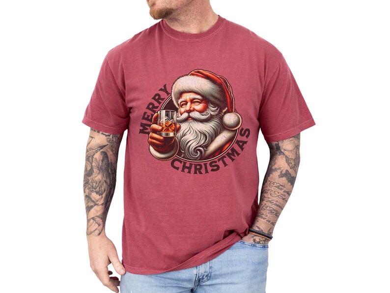 Christmas drinking shirt graphic tee. The t shirt has a distressed, vintage Santa that is holding a glass of whiskey or bourbon on the rocks. The tshirt says Merry Christmas. Comfort Colors tee, short sleeves, crewneck